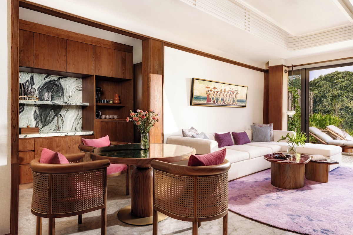A modern living room with a marble countertop, wicker chairs, a round coffee table, a white sofa, and a painting on the wall.