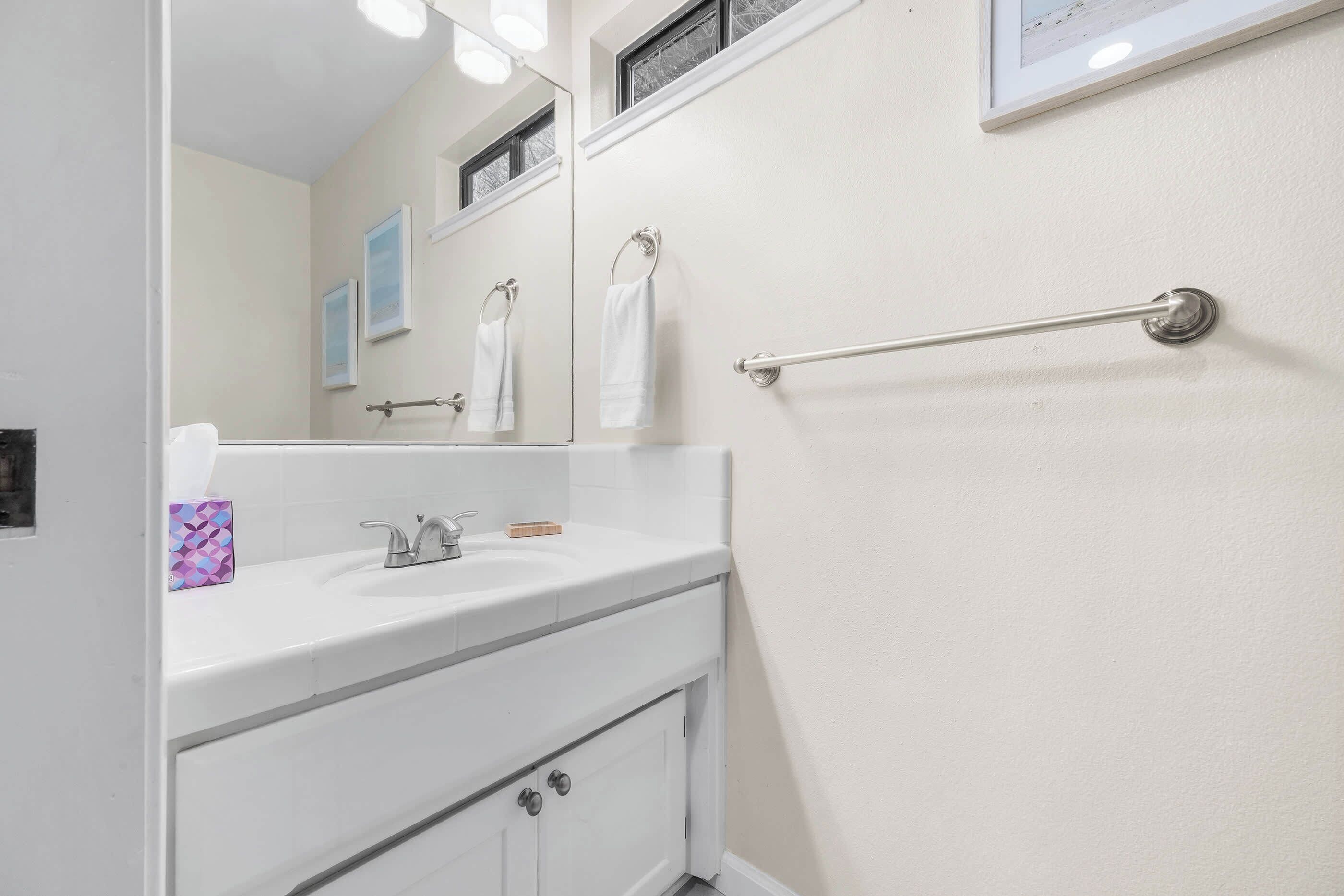 A bathroom with a white sink, mirror, and towel rack.