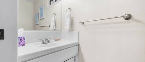 A bathroom with a white sink, mirror, and towel rack.