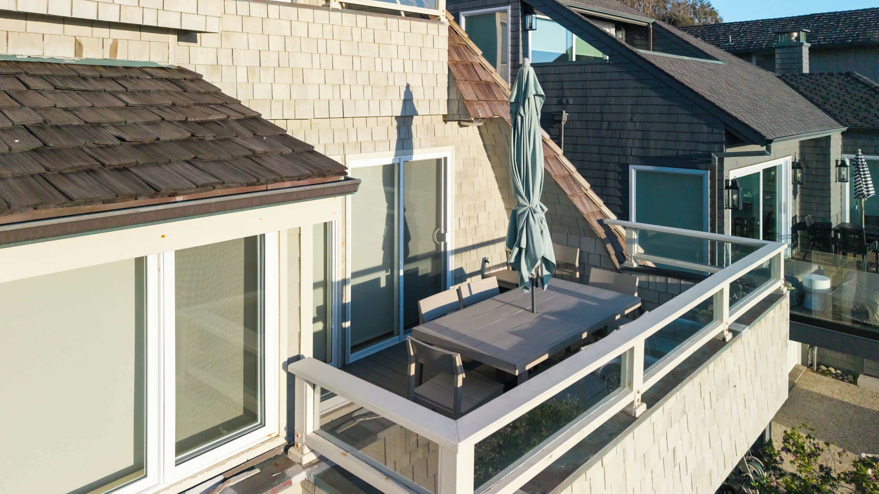 Ein Wohnbalkon mit Glasgeländer, einem Tisch und einem Stuhl.