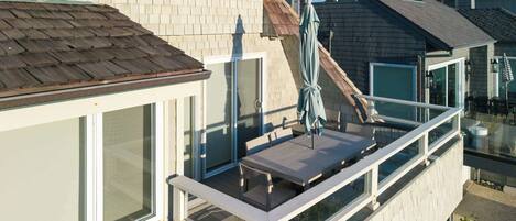 Ein Wohnbalkon mit Glasgeländer, einem Tisch und einem Stuhl.