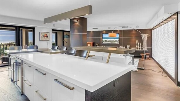 Eine moderne Küche mit einer großen Kochinsel, einer Bar und einem Fernseher.