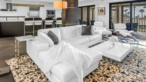 Ein modernes Wohnzimmer mit einem weißen Sofa, einem Couchtisch und einem Essbereich mit Stühlen und einem Tisch.