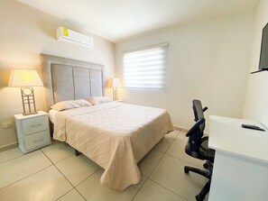Un dormitorio con cama, mesitas de noche, escritorio y una silla.