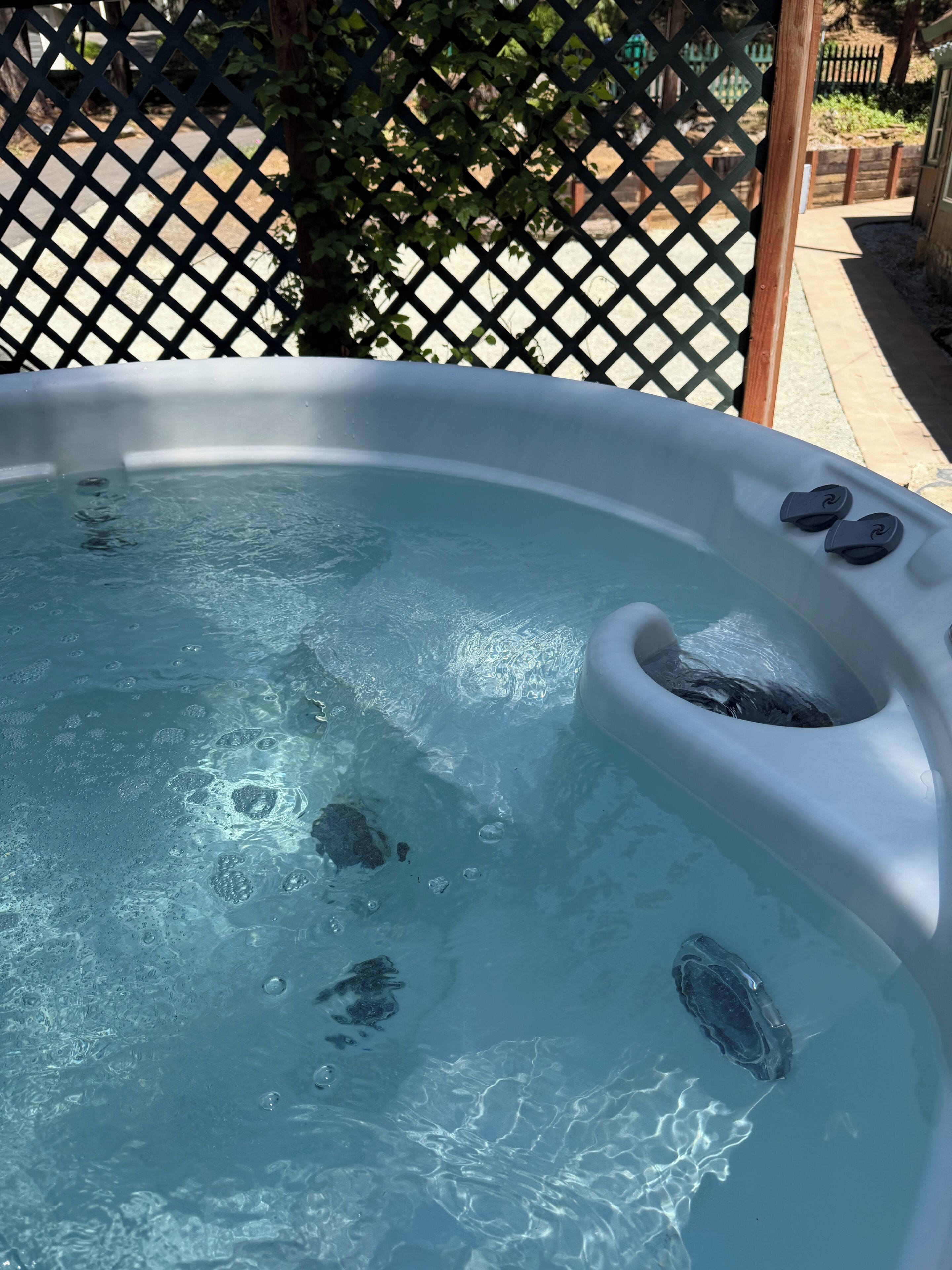 Un jacuzzi con burbujas visibles y una estructura de madera al fondo.