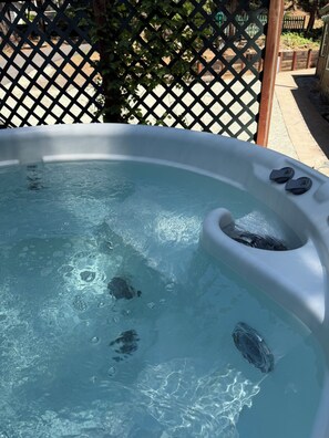 A hot tub with visible bubbles and a wooden structure in the background. - Cute Cozy Cabin (Twain Harte)