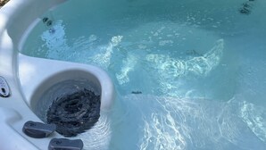 A hot tub with clear water, a drain, and a control panel. - Cute Cozy Cabin (Twain Harte)