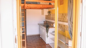 A compact kitchen with a wooden ceiling, a white sink, and a tiled backsplash. - Surfbase Vieux Boucau (Vieux-Boucau-les-Bains)