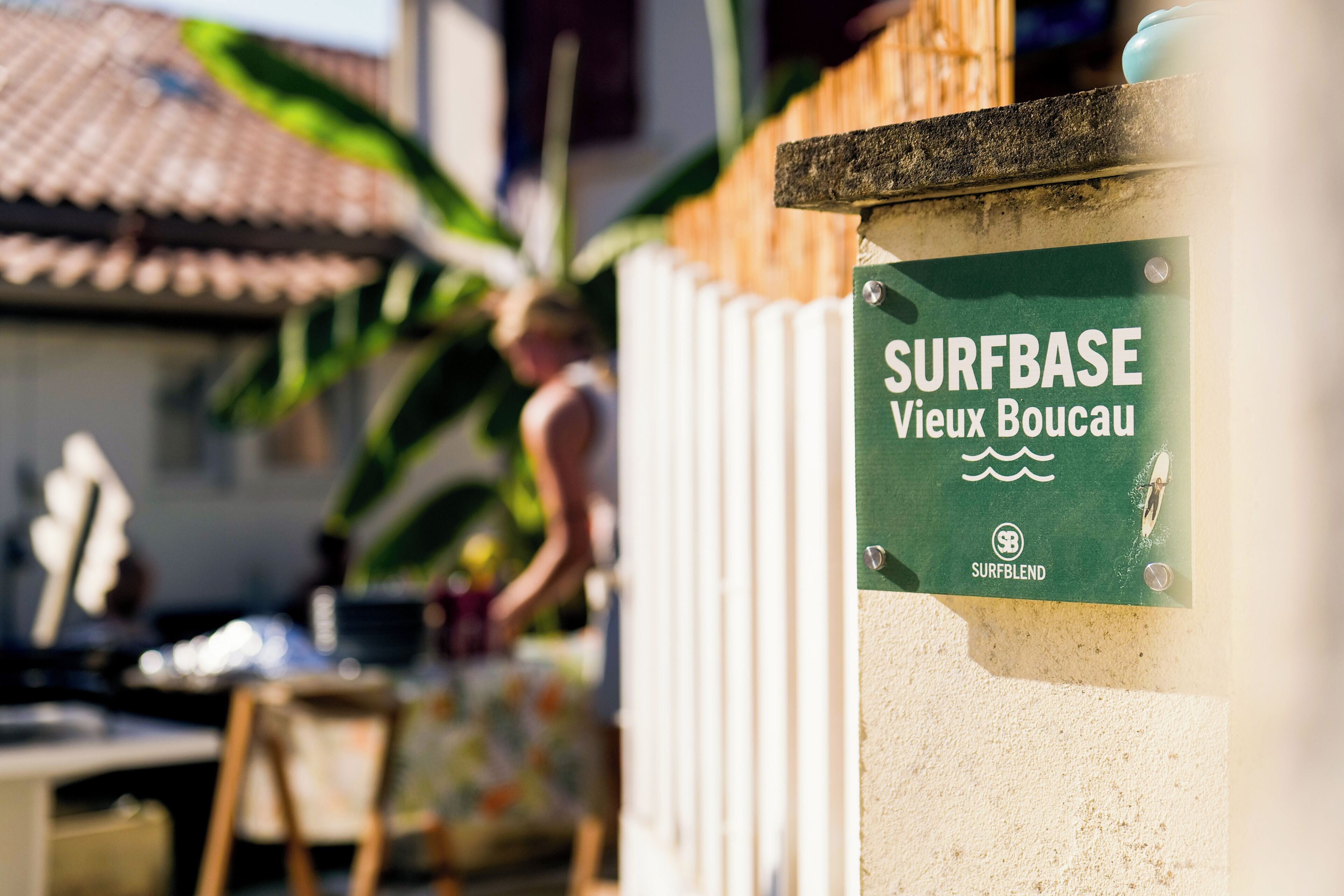 Ein Schild an einer Wand mit der Aufschrift 'SURFBASE Vieux Boucau', einem Logo und einem Wellensymbol.