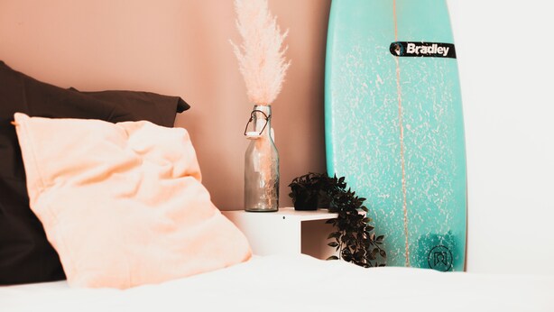 A bed with a teal surfboard, a bottle, and a plant. - Surfbase Vieux Boucau (Vieux-Boucau-les-Bains)