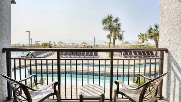 Ein Balkon mit Blick auf Pool und Strand.