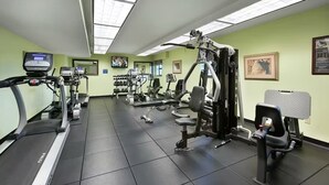 Ein Fitnessstudio mit Laufbändern, Kraftgeräten und Kurzhanteln.