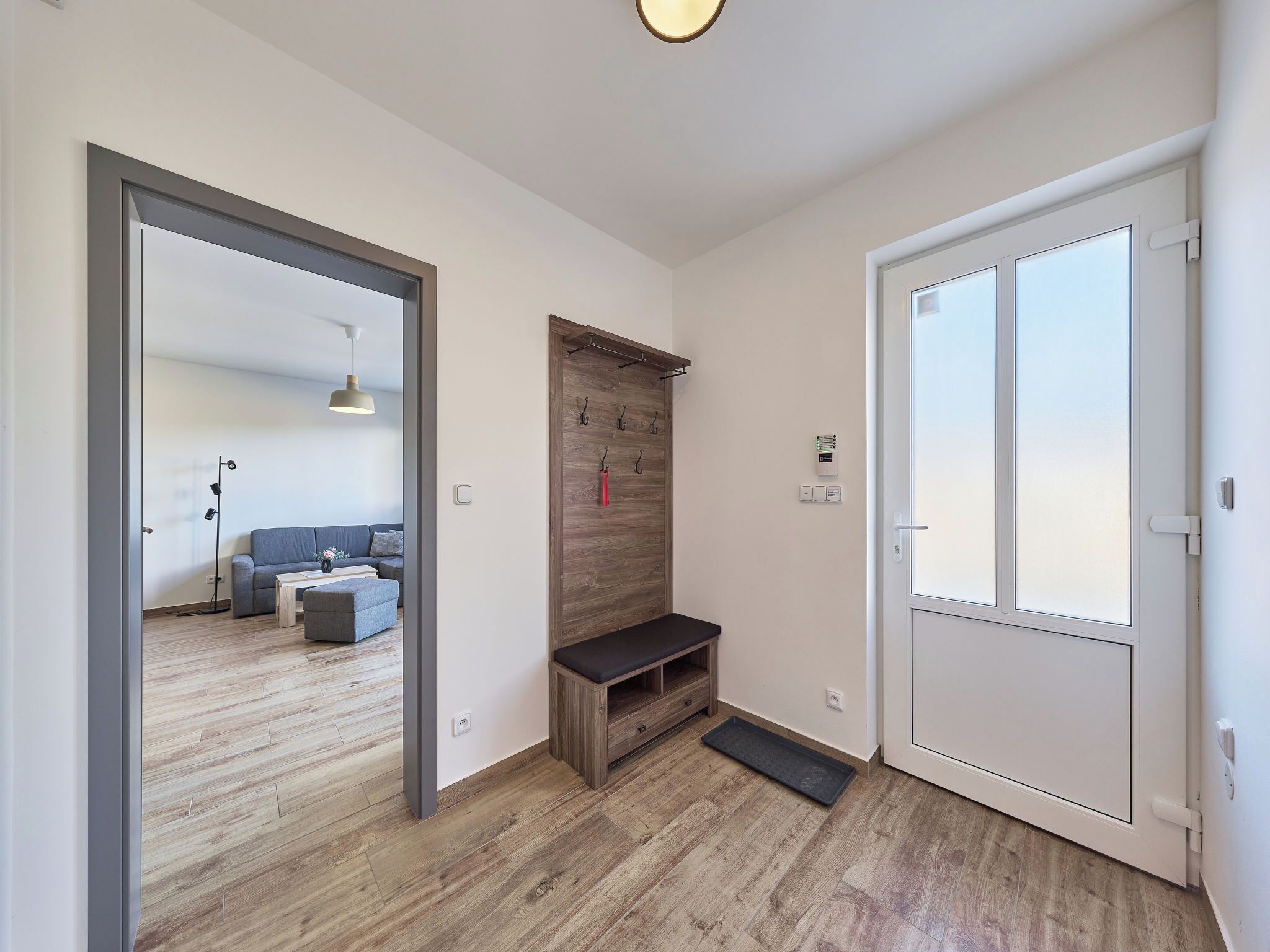 Un pasillo con un banco de madera, una puerta y una lámpara.