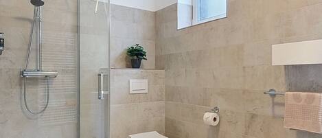 A modern bathroom with a glass-enclosed shower, a toilet, and a towel rack.