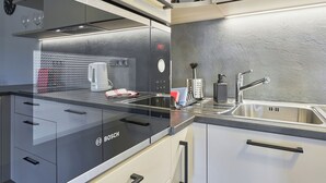 Une cuisine moderne équipée d’appareils électroménagers Bosch, d’un évier en acier inoxydable et d’un pare-éclaboussures en verre.
