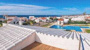 A rooftop terrace with a wooden deck, a swimming pool, and white buildings with red roofs in the background. - Biniroma by 3 Villas Menorca (Binibéquer Vell)