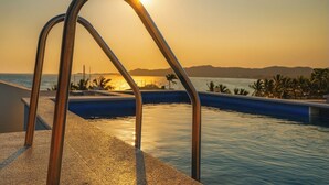 Une vue sur la piscine, avec des garde-corps en métal et un coucher de soleil en arrière-plan.