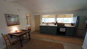 A spacious kitchen with a dining area, wooden chairs, a rug, and a painting on the wall. - Cozy and private one-bedroom studio in Bishop (Bishop)