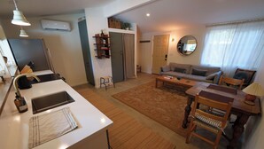 A modern living room with a sofa, coffee table, and a dining area with a table and chairs. There is a kitchen area with a sink and a countertop. - Cozy and private one-bedroom studio in Bishop (Bishop)