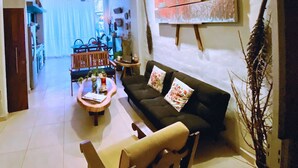Ein Wohnzimmer mit einer Couch, einem Couchtisch und Sesseln, ein Essbereich mit Tisch und Stühlen sowie ein Deckenventilator.