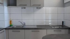 A modern kitchen with white cabinets, a black countertop, and a round table. - Studio near Basel Airport RM1142 (Saint-Louis)