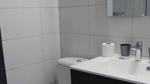 A modern bathroom with a toilet, sink, and mirror. - Studio near Basel Airport RM1142 (Saint-Louis)