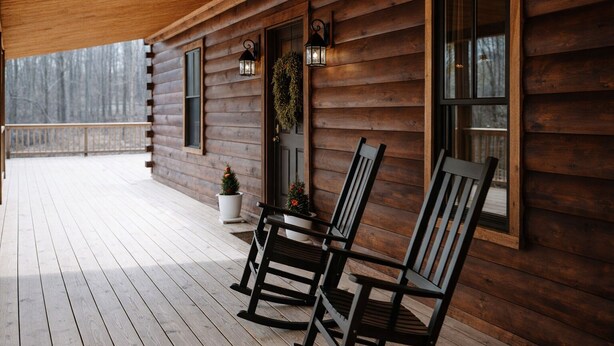 A wooden cabin with a porch, rocking chairs, and potted plants. - Cozy 1-bedroom cabin in the Hocking Hills of Ohio (Londonderry)
