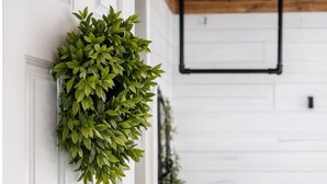A white door with a green wreath, a wooden ceiling, and a white wall with a bed and dresser in the background. - Cozy 1-bedroom cabin in the Hocking Hills of Ohio (Londonderry)