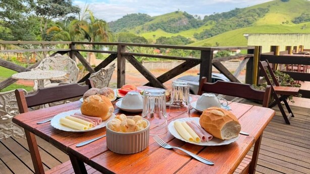 Mesa de madera al aire libre con platos de comida, un bol de pasteles y un vaso de agua.