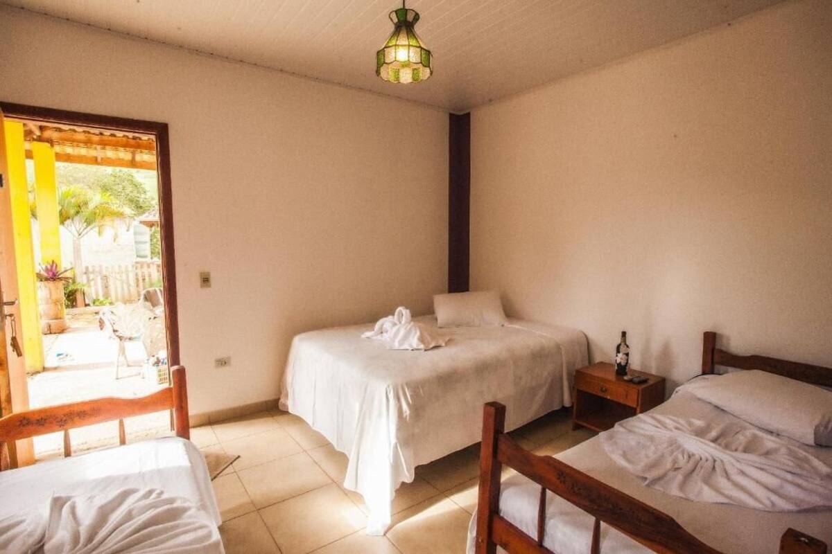 A room with two beds, a wooden headboard, a nightstand, and a hanging light fixture.