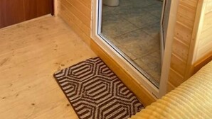 A small, compact bathroom with a wooden floor, a sink, a toilet, and a mirror. - Guest house River side  (Mestia)