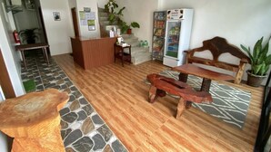 A reception area with a wooden bench, a reception desk, a refrigerator, and a potted plant. - Cozy Stay at Jezette’s Inn (Barangay 5, Sipalay City)