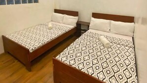 Una habitación con dos camas de madera, una ventana con diseño de celosía y un techo de madera con iluminación empotrada.