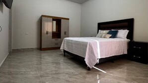 A bedroom with a bed, a wardrobe, a nightstand, and a flat-screen TV mounted on the wall. - Villa Idalia (Comayagua)