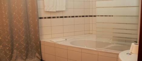 A bathroom with a bathtub, toilet, and shower curtain.