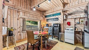 A rustic wooden interior with a dining area, kitchen, and a sign indicating a coffee and tea service.