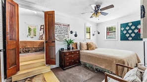A bedroom with a bed, a dresser, a ceiling fan, and a wall-mounted clock. - Charming Downtown Cottage with Free Parking (Eureka Springs)
