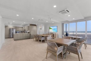 A modern kitchen with a dining area, large windows, and a view of the beach. - Beachfront Condo on Bonita Beach  - SeaGlass Shores (Bonita Springs)