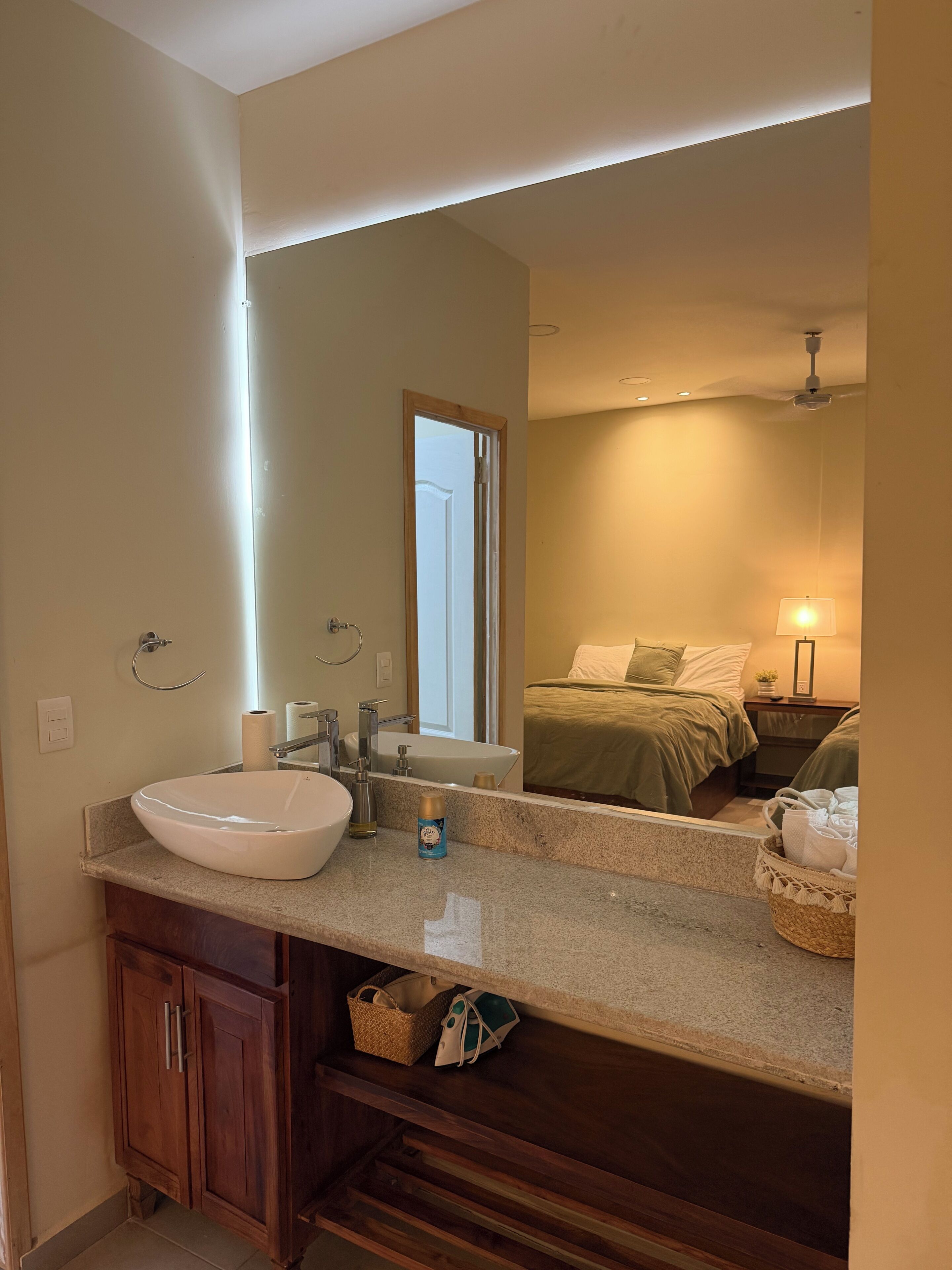 A bathroom with a large mirror, a sink, a bathtub, wooden cabinets, and a towel rack.