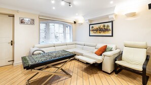 A modern living room with a sectional sofa, a small table, and a reclining chair. - Classic Pimlico Townhouse (London)