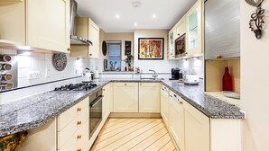 A modern kitchen with granite countertops, stainless steel appliances, and light-colored cabinetry. - Classic Pimlico Townhouse (London)