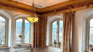 Een gezellige kamer met een houten plafond, een blauwe fauteuil, een bank en een tafel.