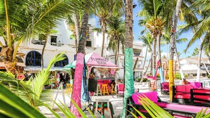Un bar situé en bord de mer, avec des sièges aux couleurs vives et des palmiers.