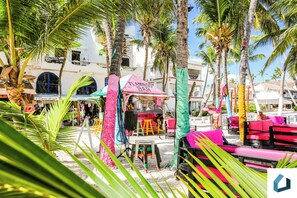 A beachside bar with colorful seating and palm trees. - Memorable Beach-front Complex Fun Pools Dine Shop (Punta Cana)