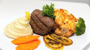 Une assiette comprenant un steak grillé, de la purée de pommes de terre, des légumes grillés et un morceau de brocoli.