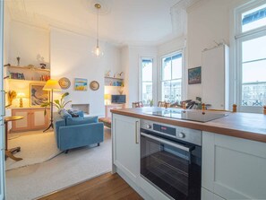 Una cocina moderna con una isla central, horno integrado y ventanas amplias.
