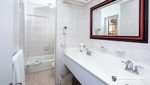 A modern bathroom with a glass shower enclosure, a large mirror with a wooden frame, and a white vanity with two sinks. - Three Bedroom Townhouse (Freeport)