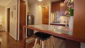 Eine moderne Küche mit Holzausstattung, einem Edelstahlkühlschrank und einem Barhocker.