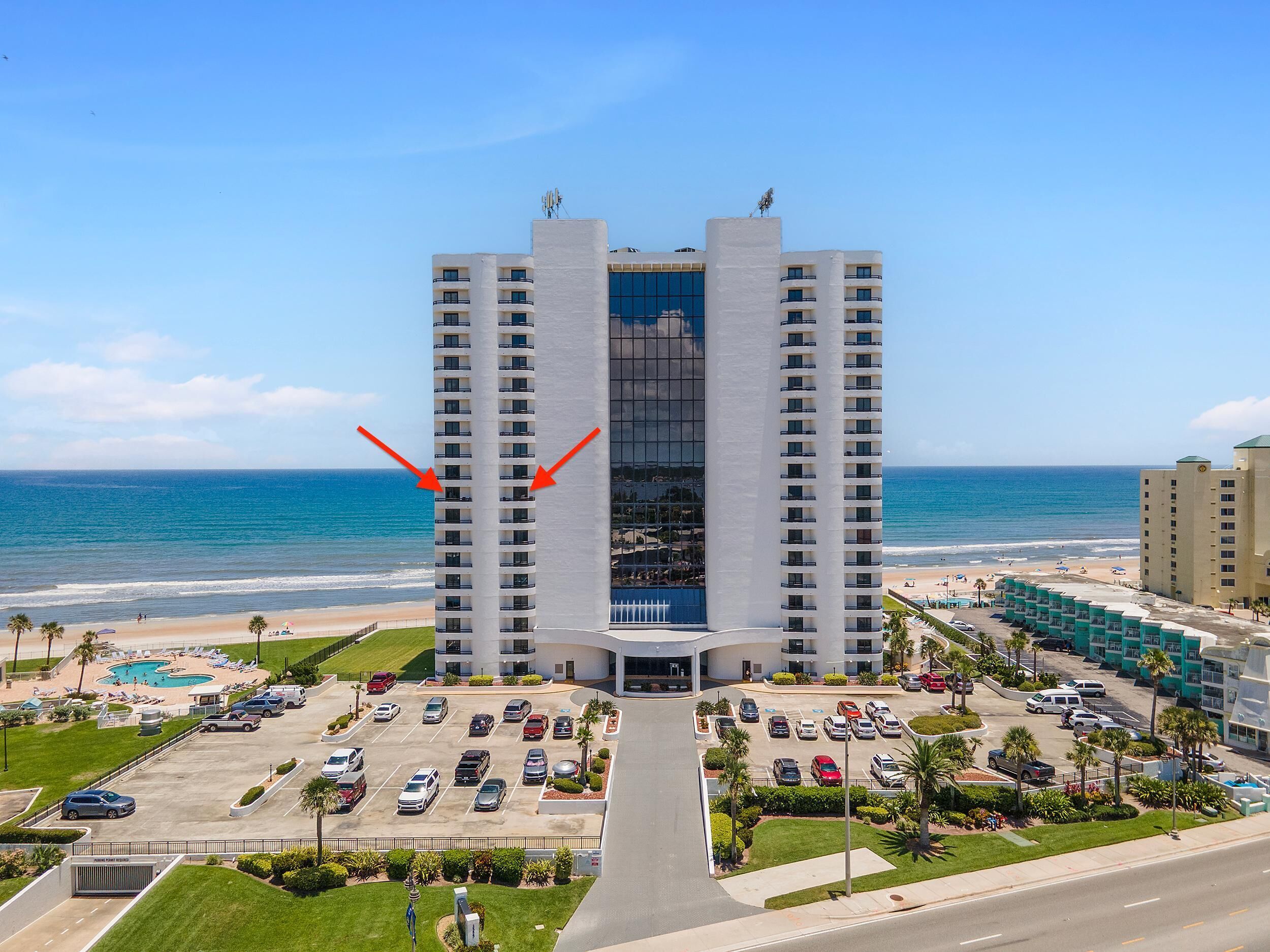 A high-rise hotel with a central atrium, a pool area, and a beach view.