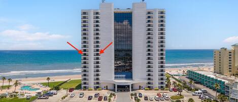 A high-rise hotel with a central atrium, a pool area, and a beach view.